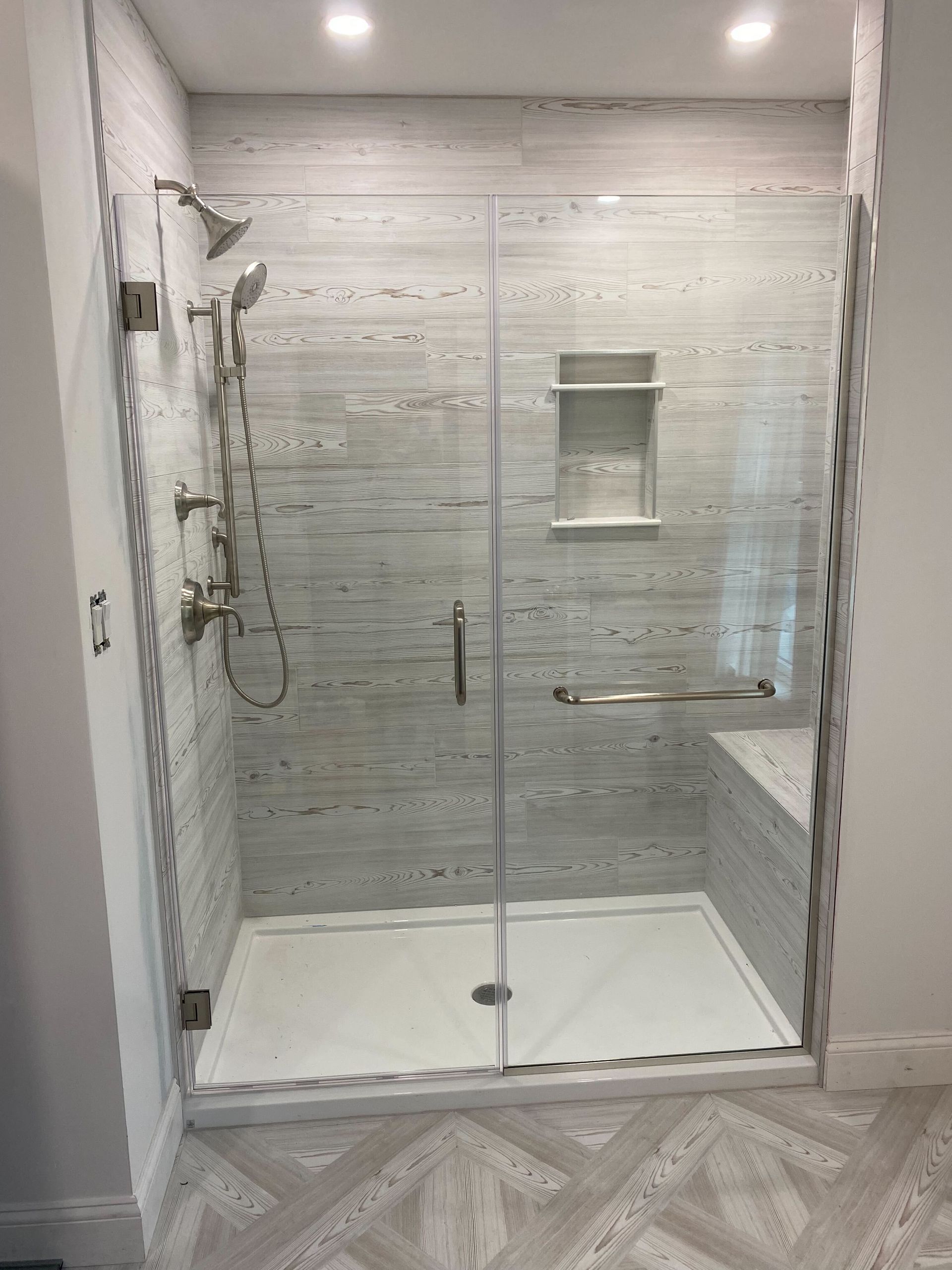 A bathroom with a walk in shower with a glass door.