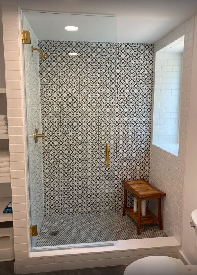 A bathroom with a walk in shower and a wooden bench.