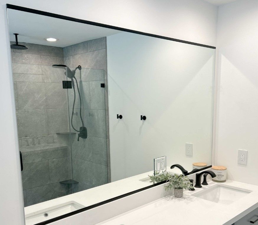 A bathroom with a large mirror over a sink and a shower.