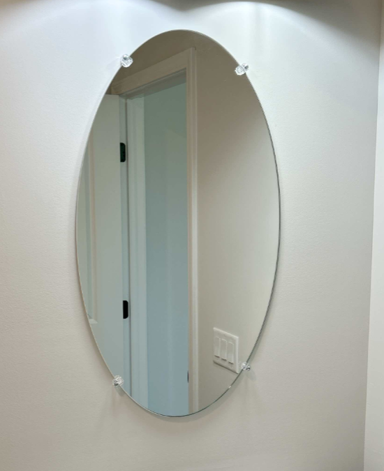 An oval mirror is hanging on a white wall.