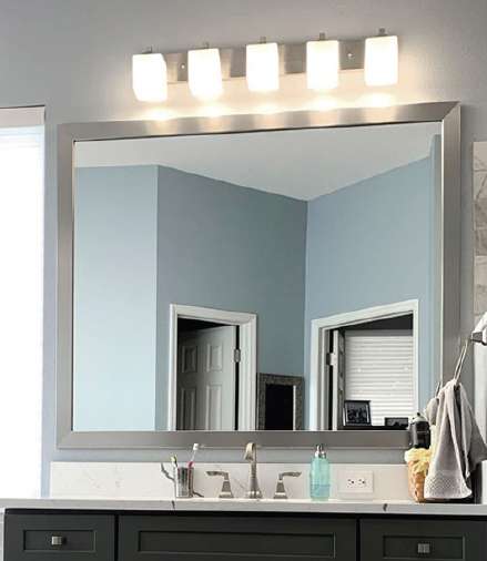 A bathroom with a large mirror over a sink.