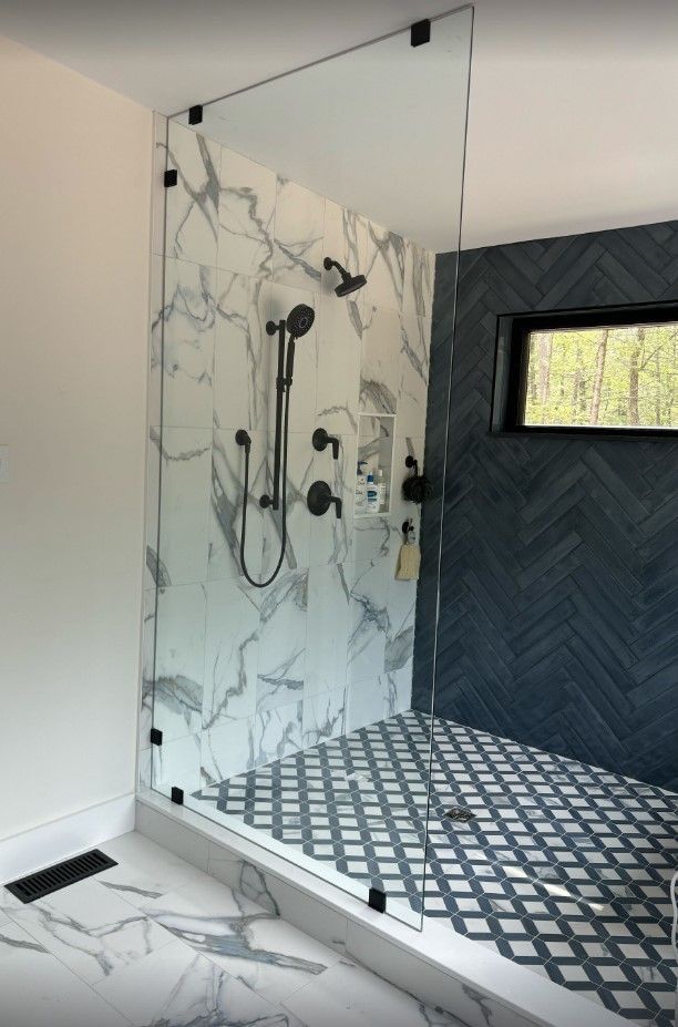 A bathroom with a walk in shower and a window.