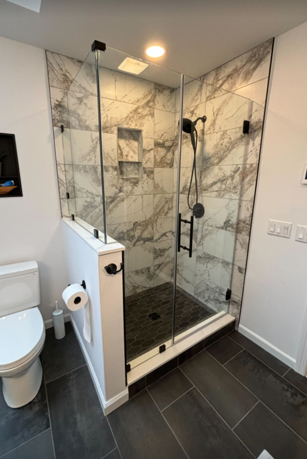 A bathroom with a toilet and a walk in shower with a glass door.