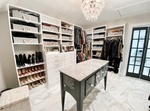 A walk in closet with a large island in the middle of it.