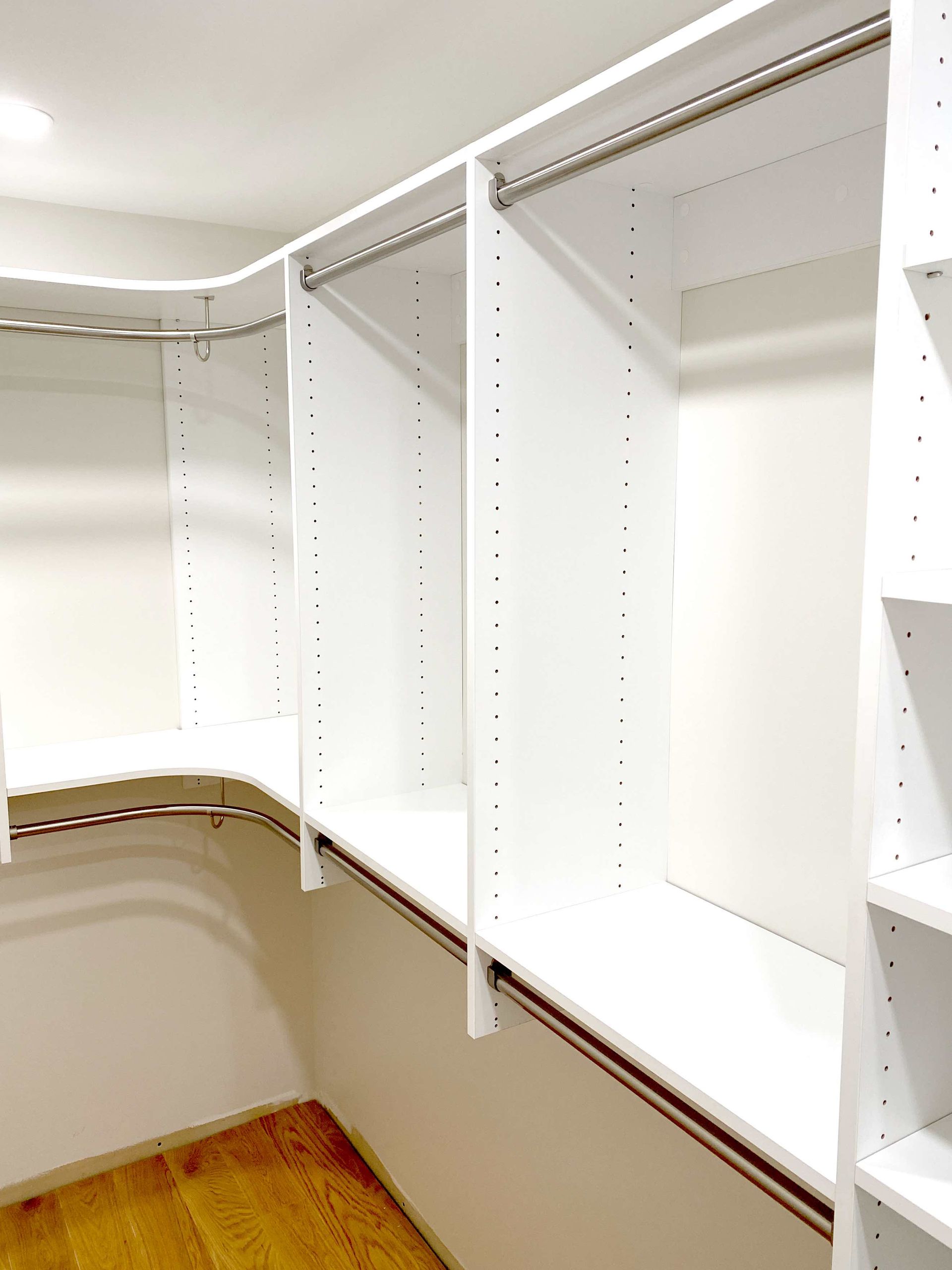 A walk in closet with lots of shelves and clothes racks.