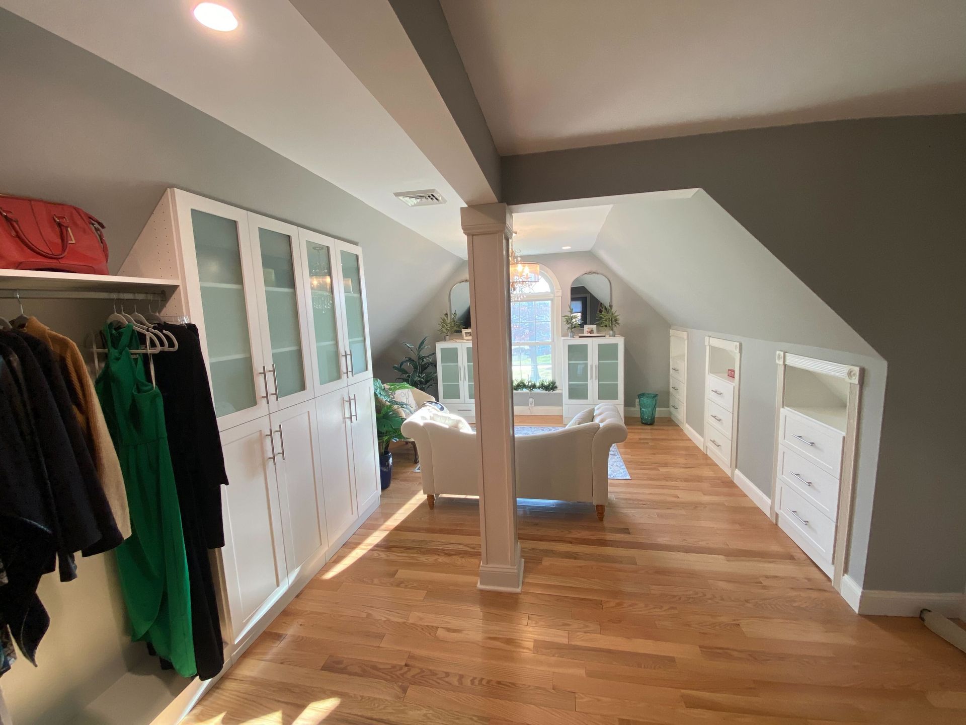 A walk in closet in an attic with a couch and cabinets.