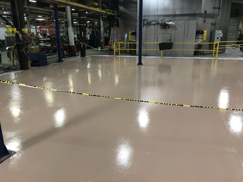 A large warehouse with a shiny floor and a yellow tape.