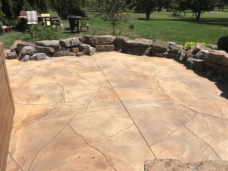 A patio with a fire pit and a table and chairs in the background.