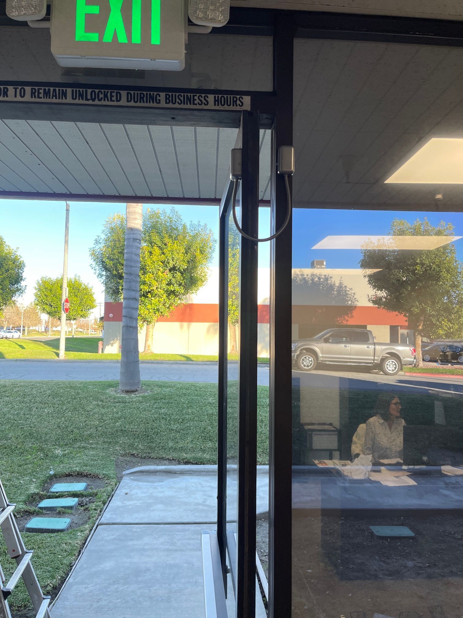 A green exit sign is above a glass door