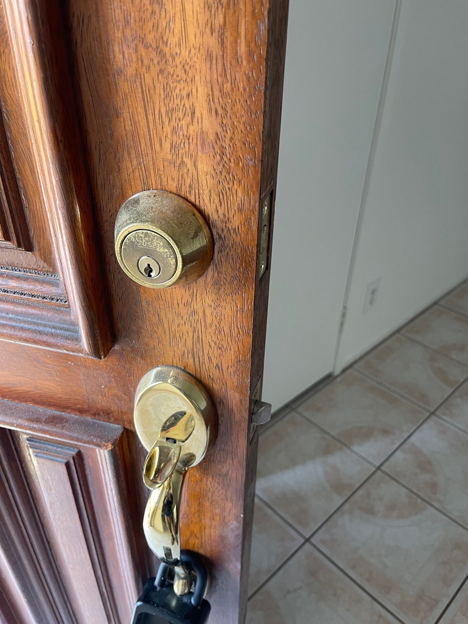 A close up of a wooden door with a padlock and keys.