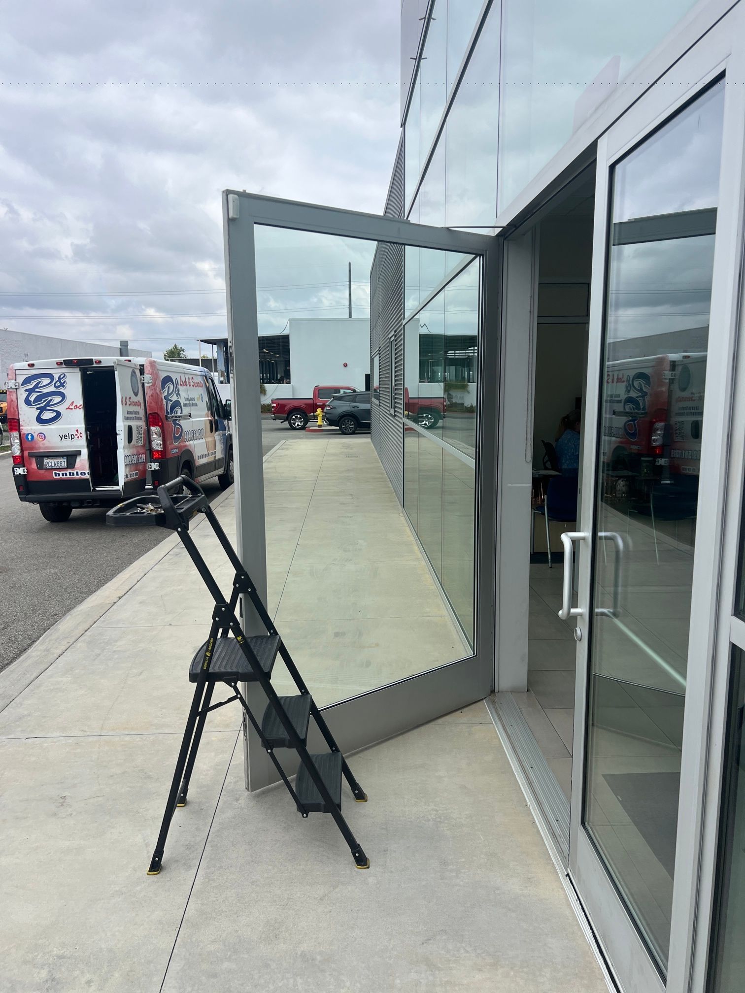 A large mirror is sitting on the sidewalk in front of a glass door.