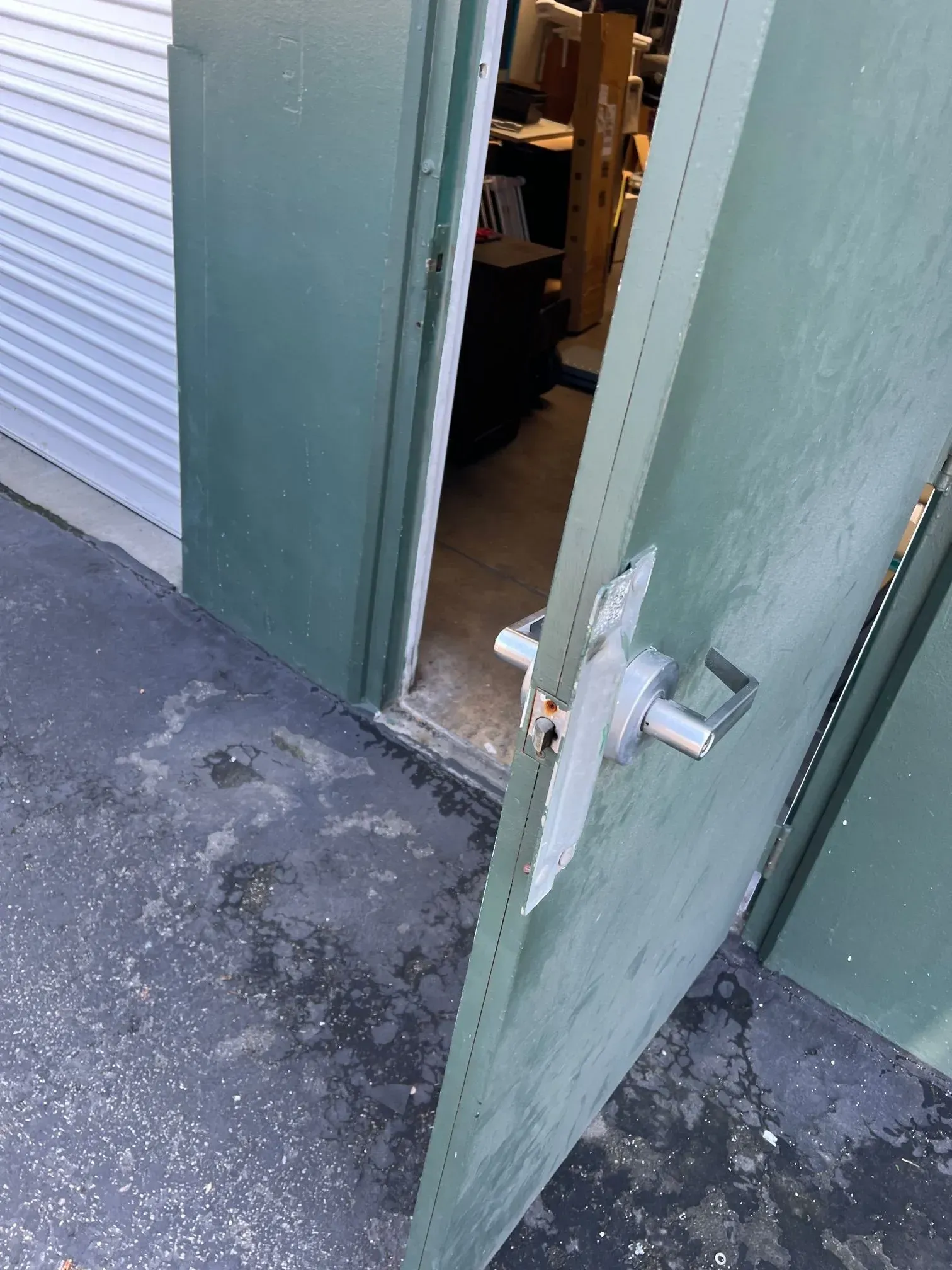 A green door with a white handle is open to a room.