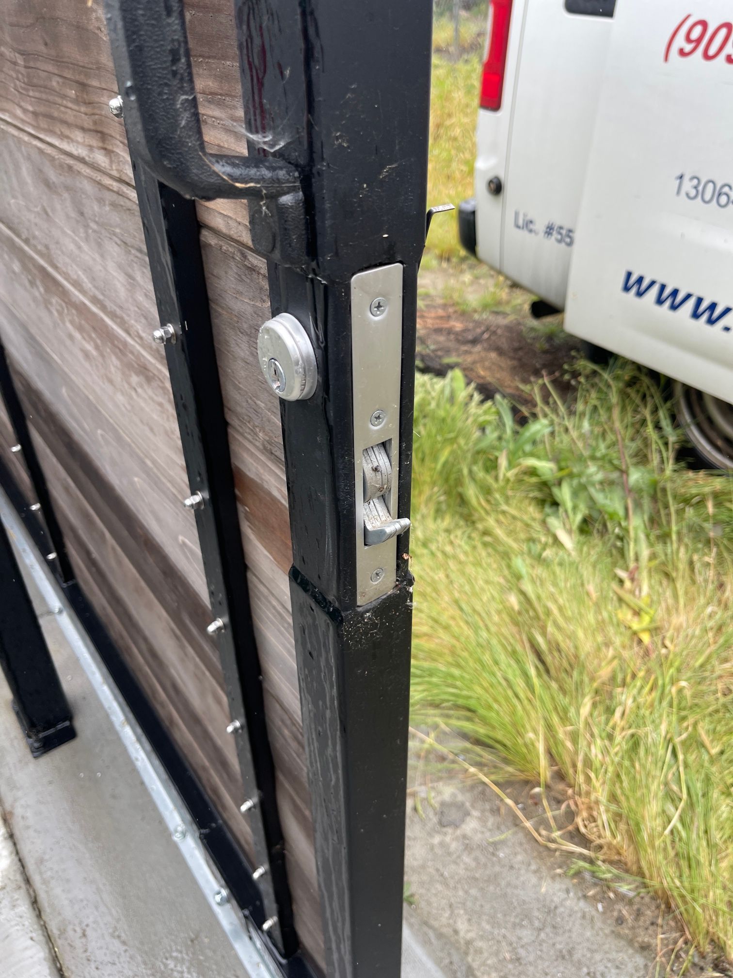 A white van is parked next to a wooden fence.