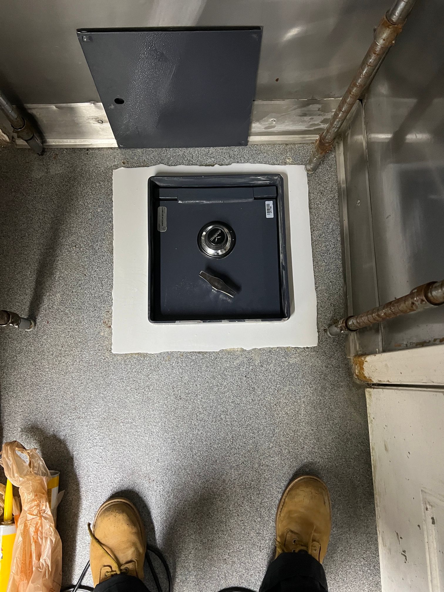 A person is standing next to a safe in a room.