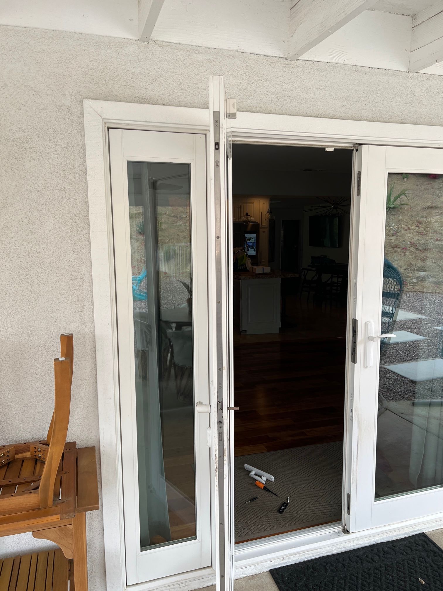 A white sliding glass door is open to a living room.