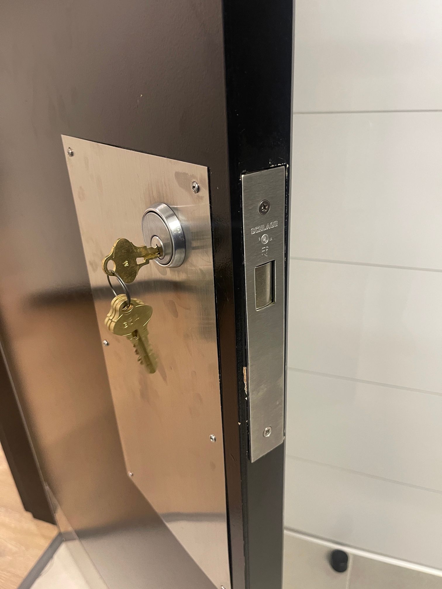 A close up of a door lock with two keys in it.