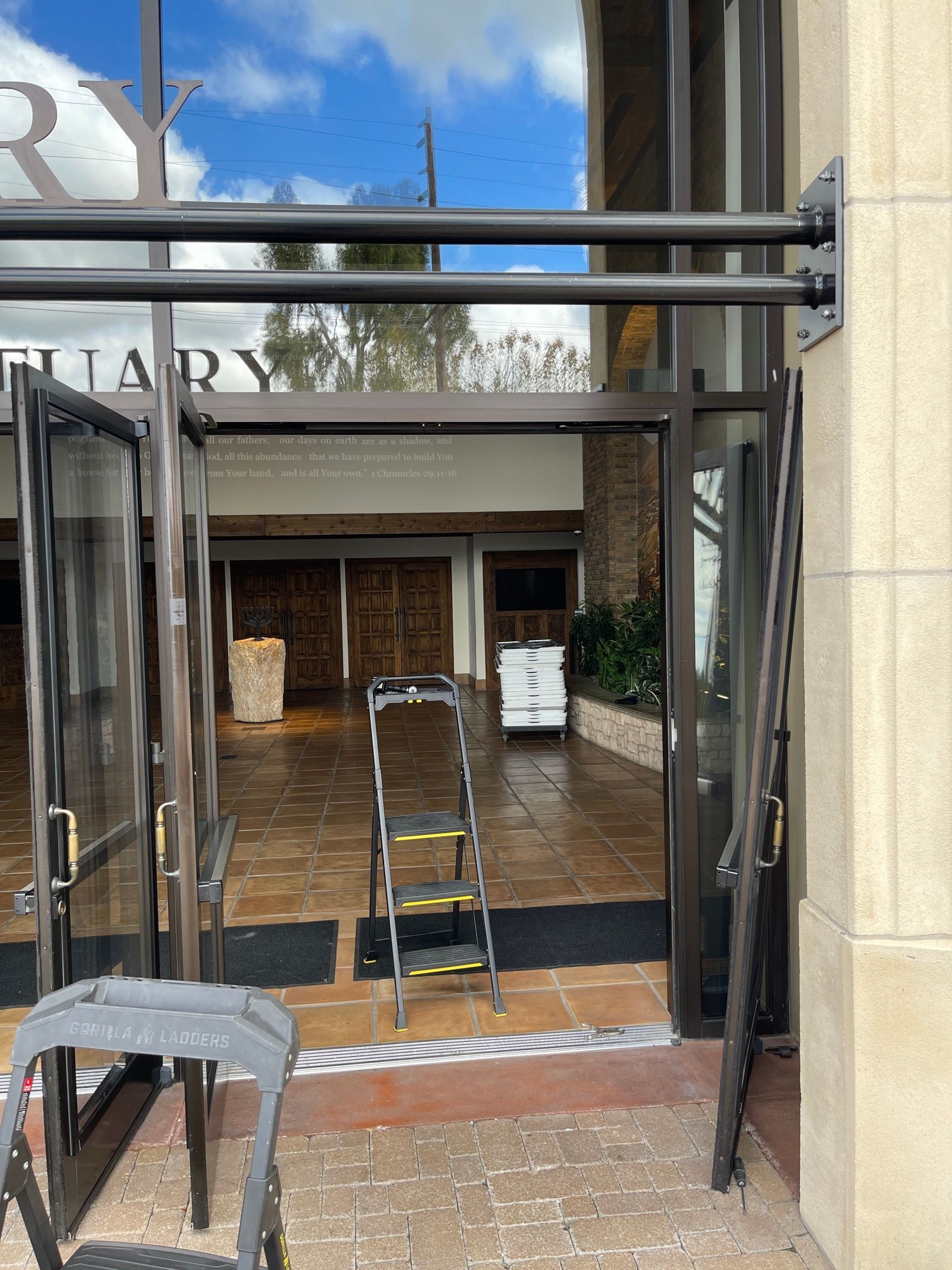 A ladder is sitting in front of a glass door.
