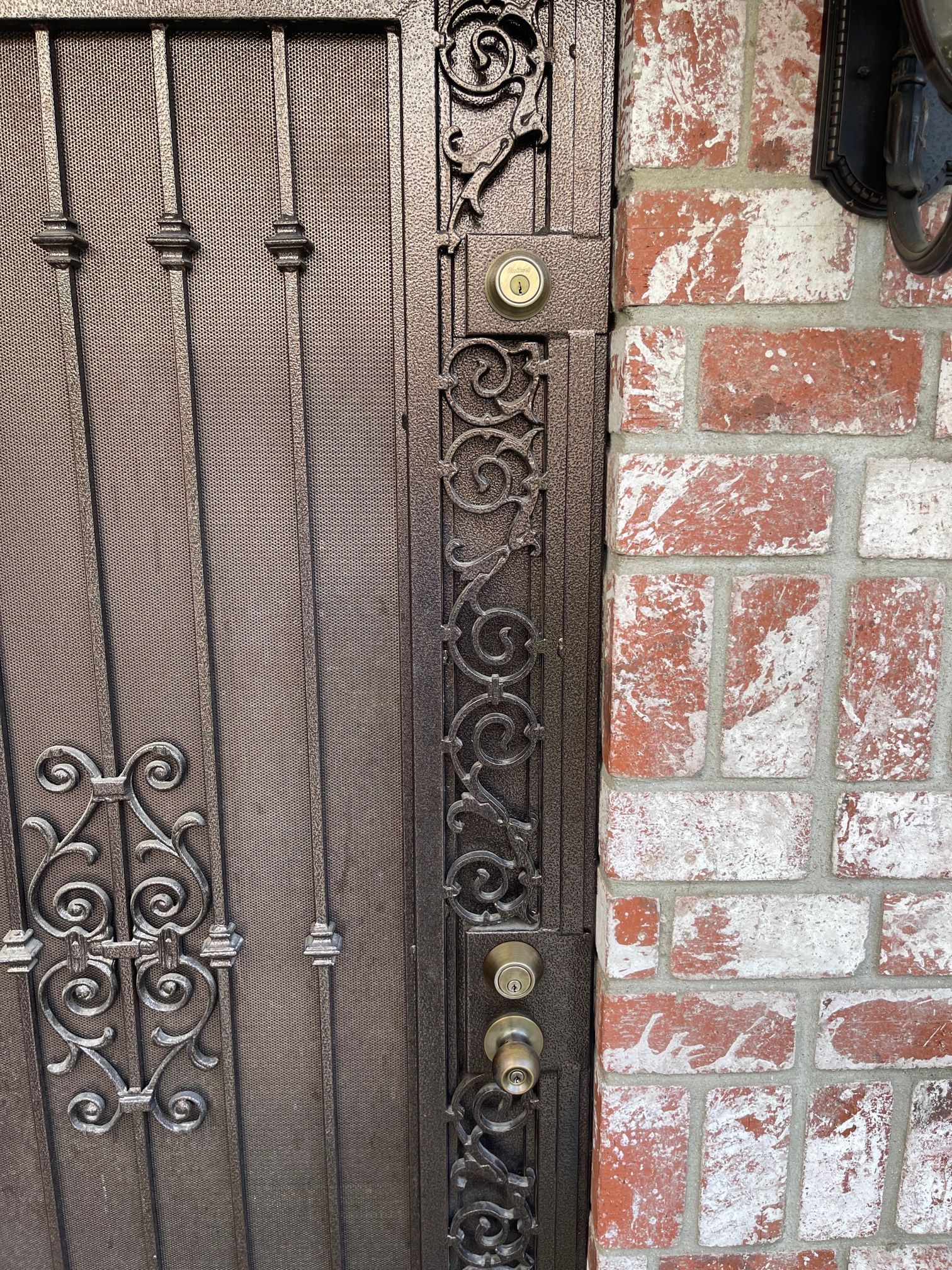 A close up of a wrought iron gate on a brick wall.