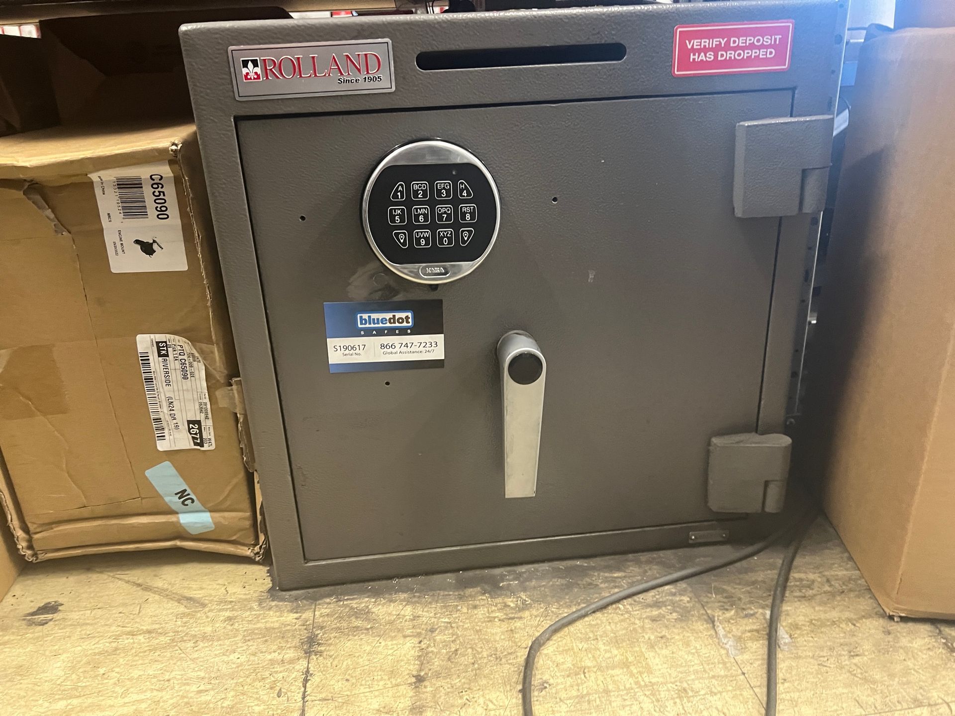 A safe is sitting on the floor next to boxes.