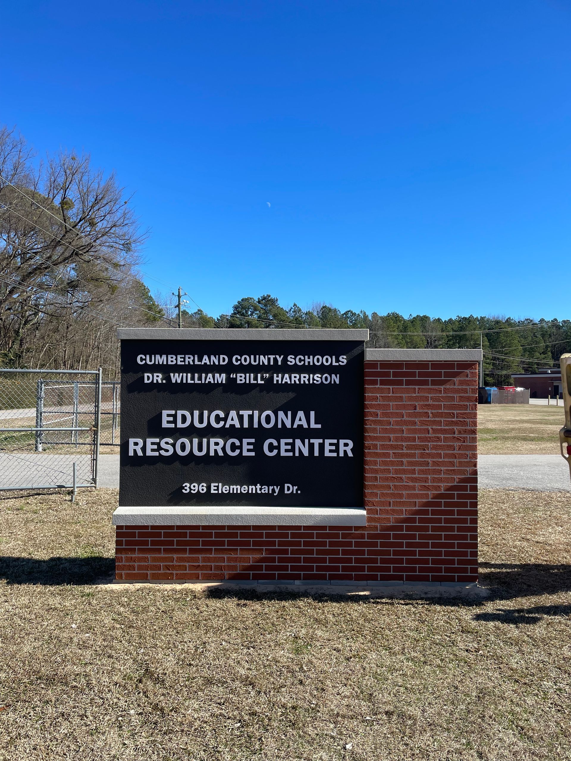 A sign for the educational resource center is sitting in the middle of a dirt field.