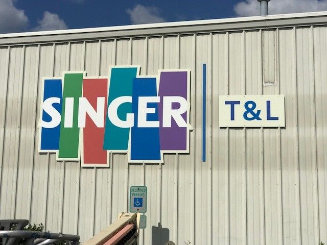 A sign on the side of a building that says singer t & l