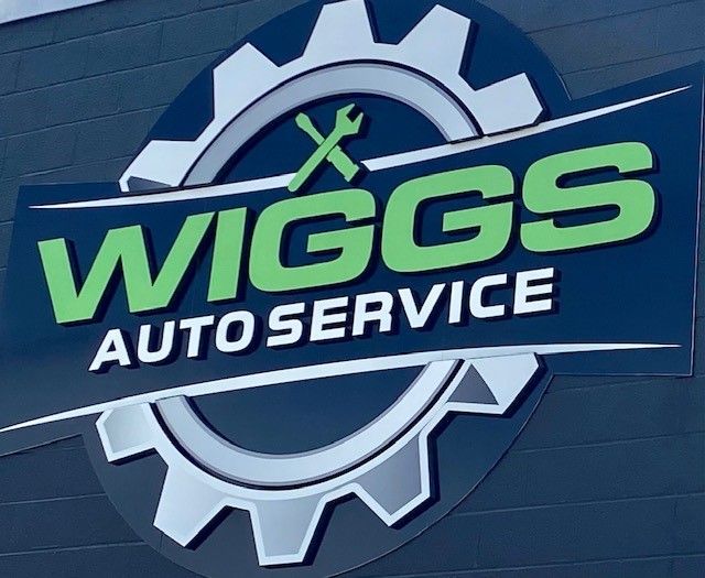 A sign for wiggs auto service with a gear and wrench
