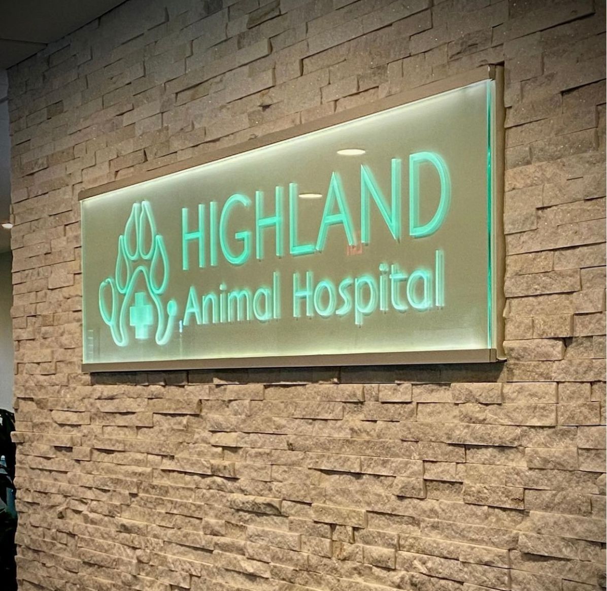 A sign that says highland animal hospital on a brick wall