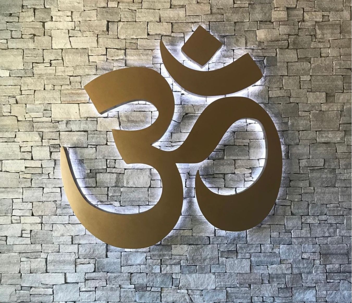 A gold om symbol on a brick wall