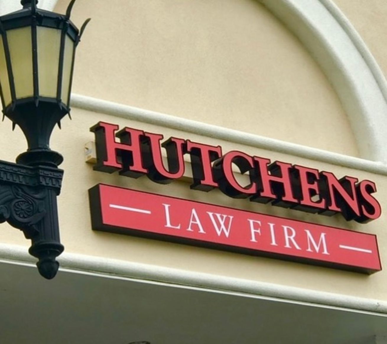 A sign for hutchens law firm hangs from a lamp post