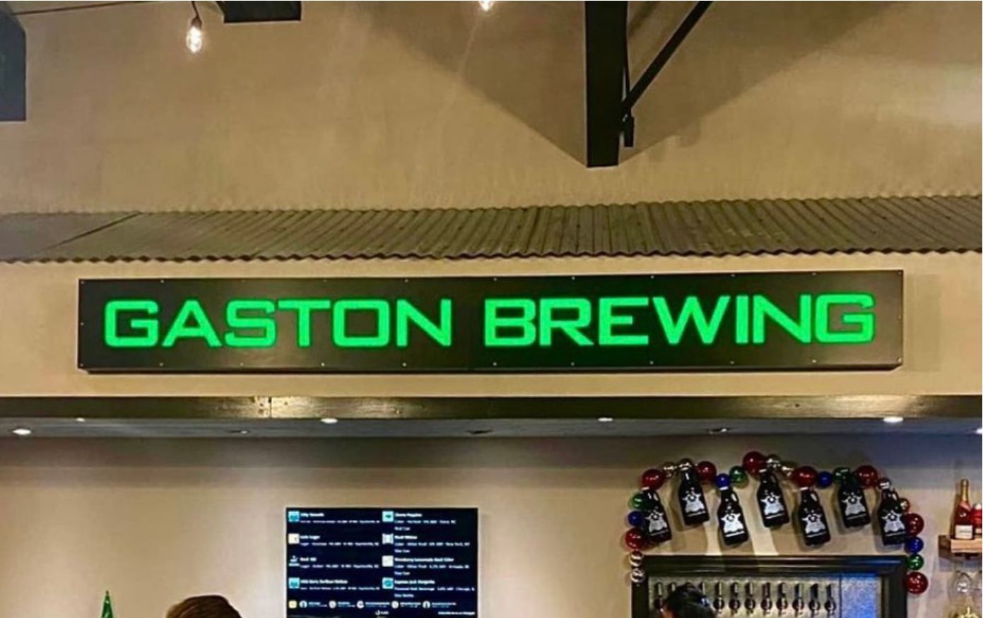 A green sign that says gaston brewing on it