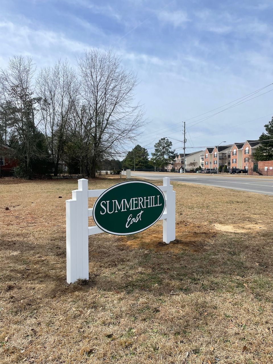 A sign for summerhill fort is sitting in the middle of a field.