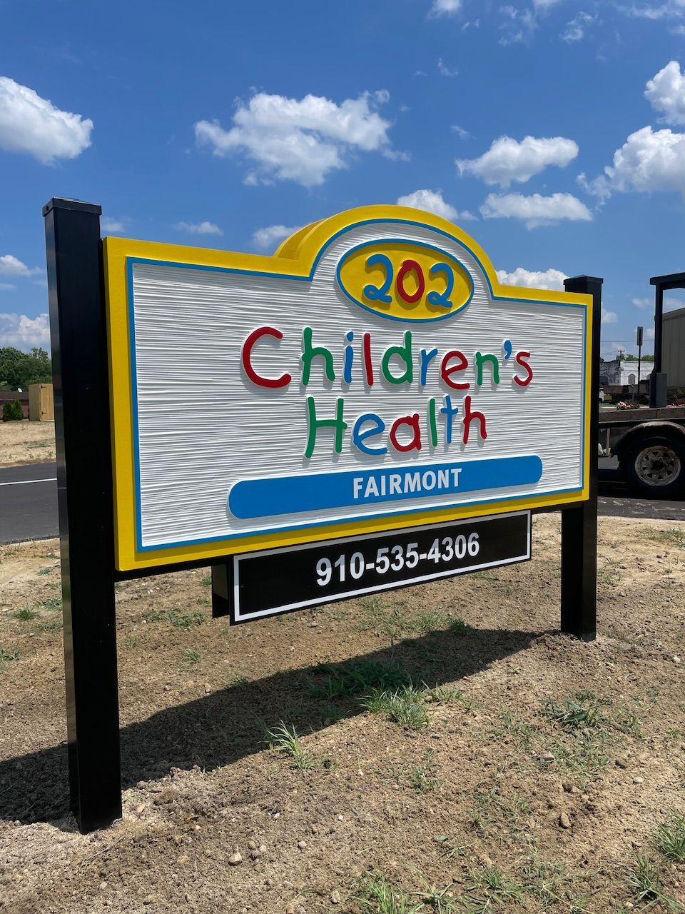 A children 's health sign is sitting in the middle of a field.