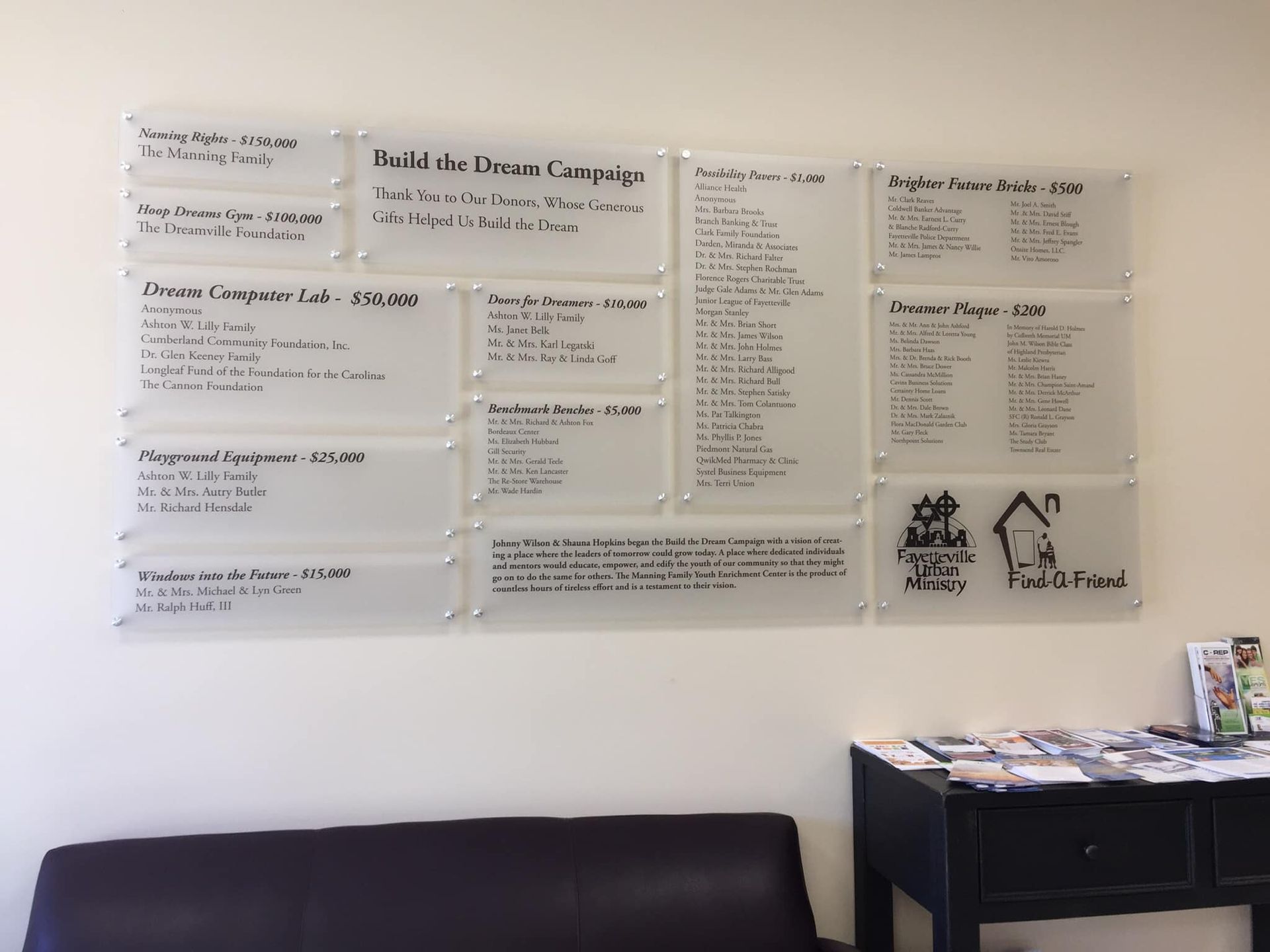 A waiting room with a couch and a table with signs on the wall