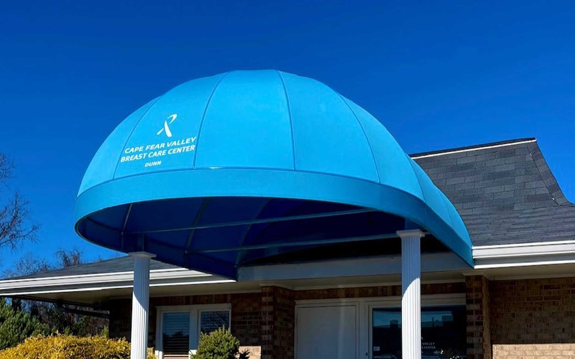 A blue awning is over the entrance to a brick building.
