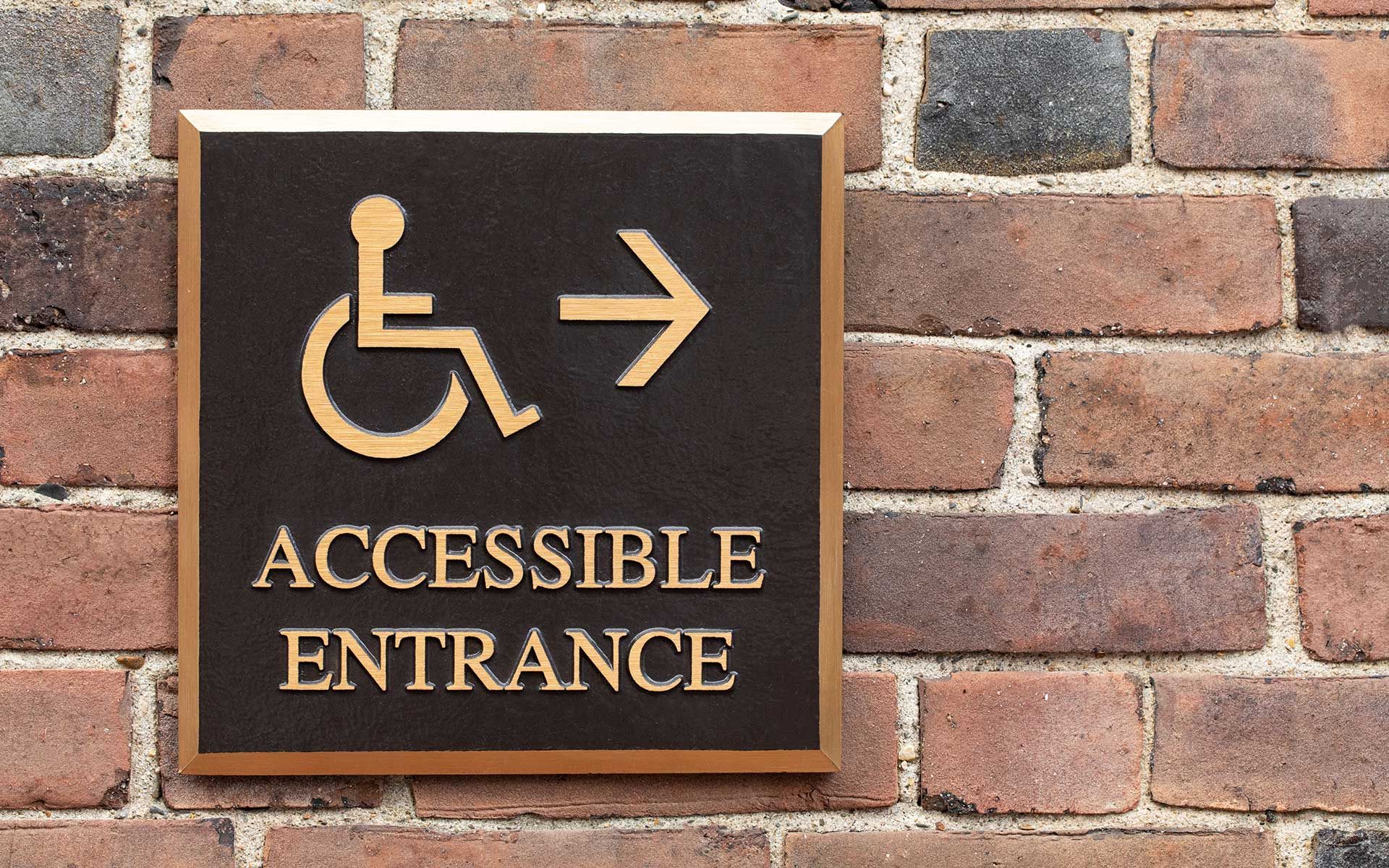 A sign on a brick wall that says accessible entrance