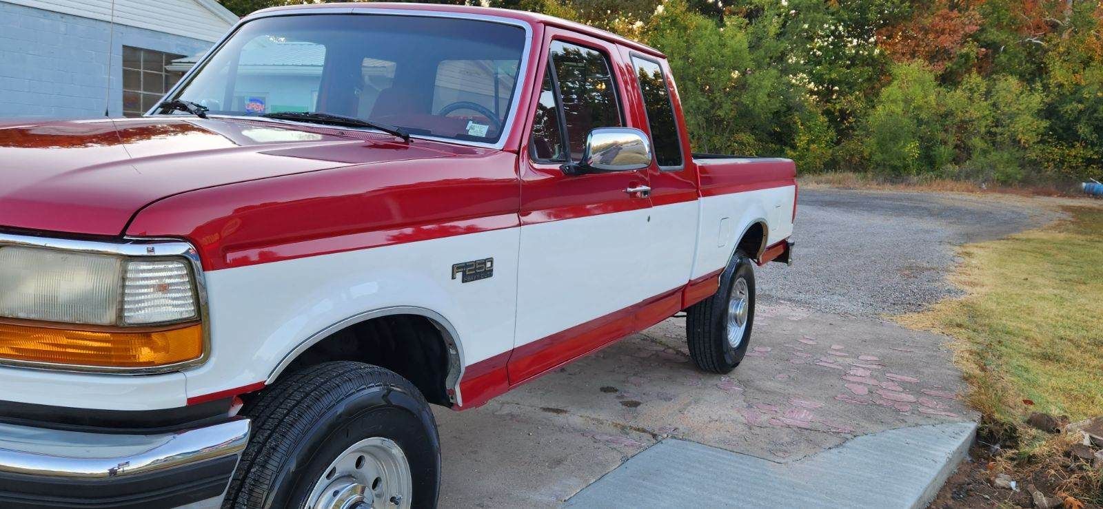a repainted red and white pickup truck is parked on the side of the road.