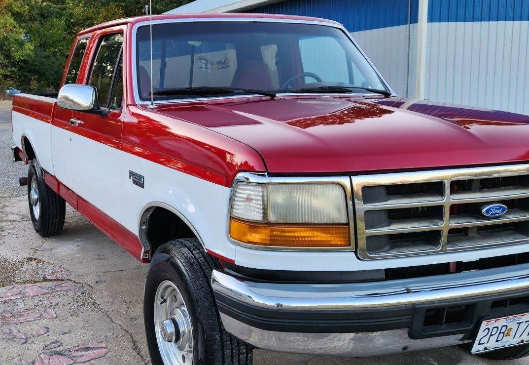 a red and white ford truck is parked in a parking lot.