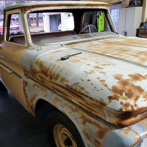 an old rusty pickup truck is parked in a garage.