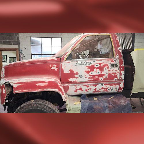 a red truck is being painted in a garage.