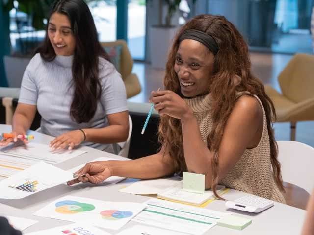 A woman smiles across the table at her coworkers