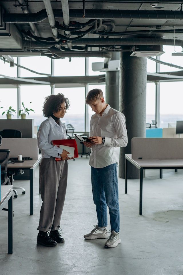 A woman instructs a man on work in a hallway