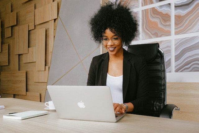 A woman smiles while working on her laptop