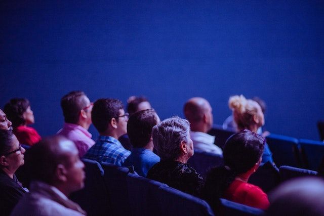 A group of people sits in a theater looking forward, at a conference