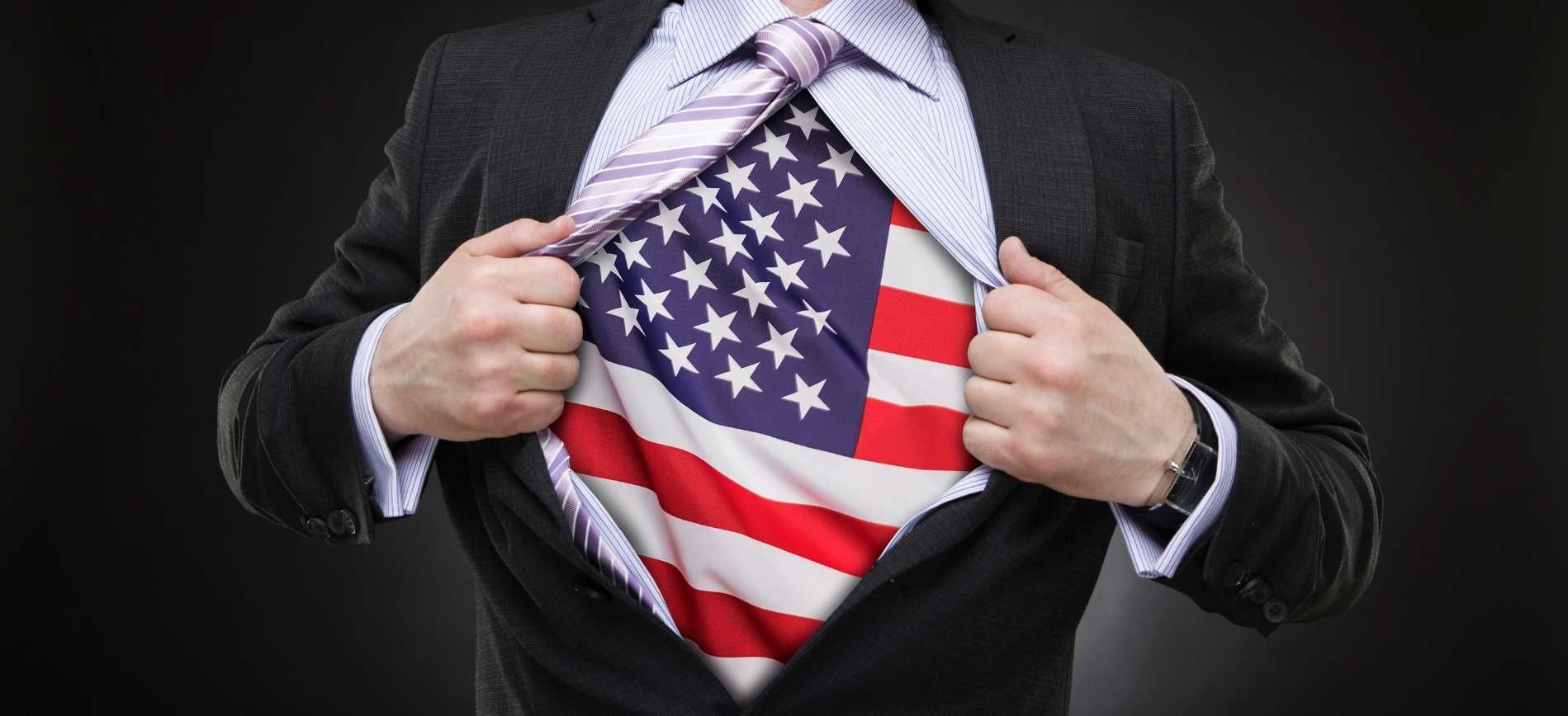 A man opens his suit and shirt to reveal a US flag underneath