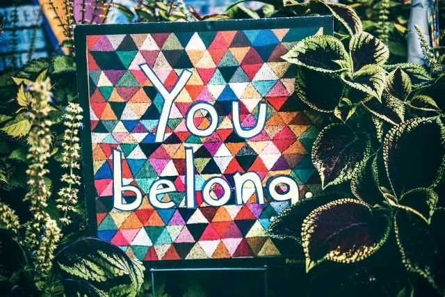 you belong spelled out in a quilted throw blanket used as wall art