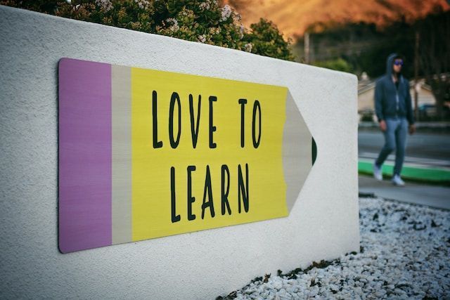 An image of a pencil on a sign. The pencil reads love to learn