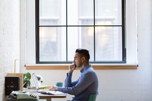 A man sites at his work station thinking