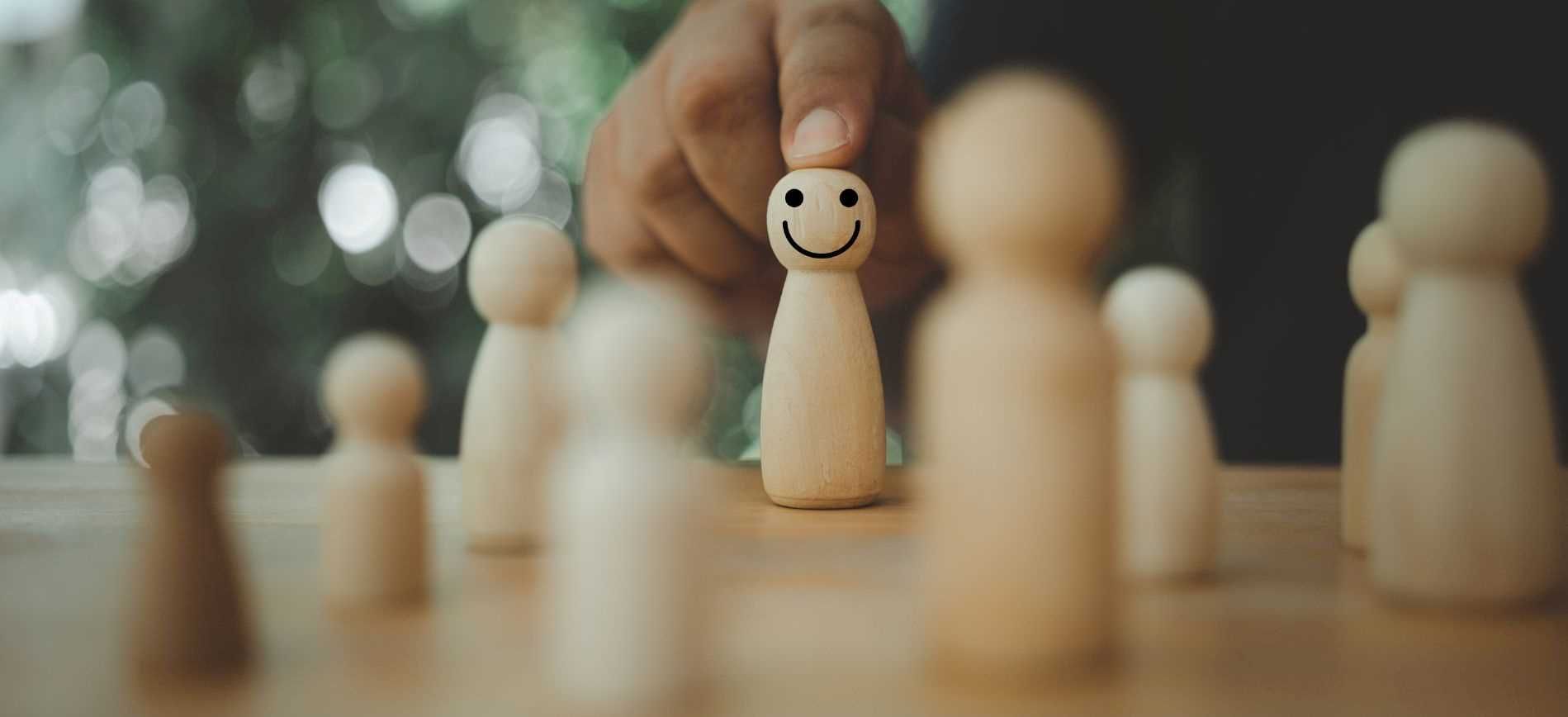 A person sits behind a chess board made of wooden pieces, in the process of moving the pieces that i