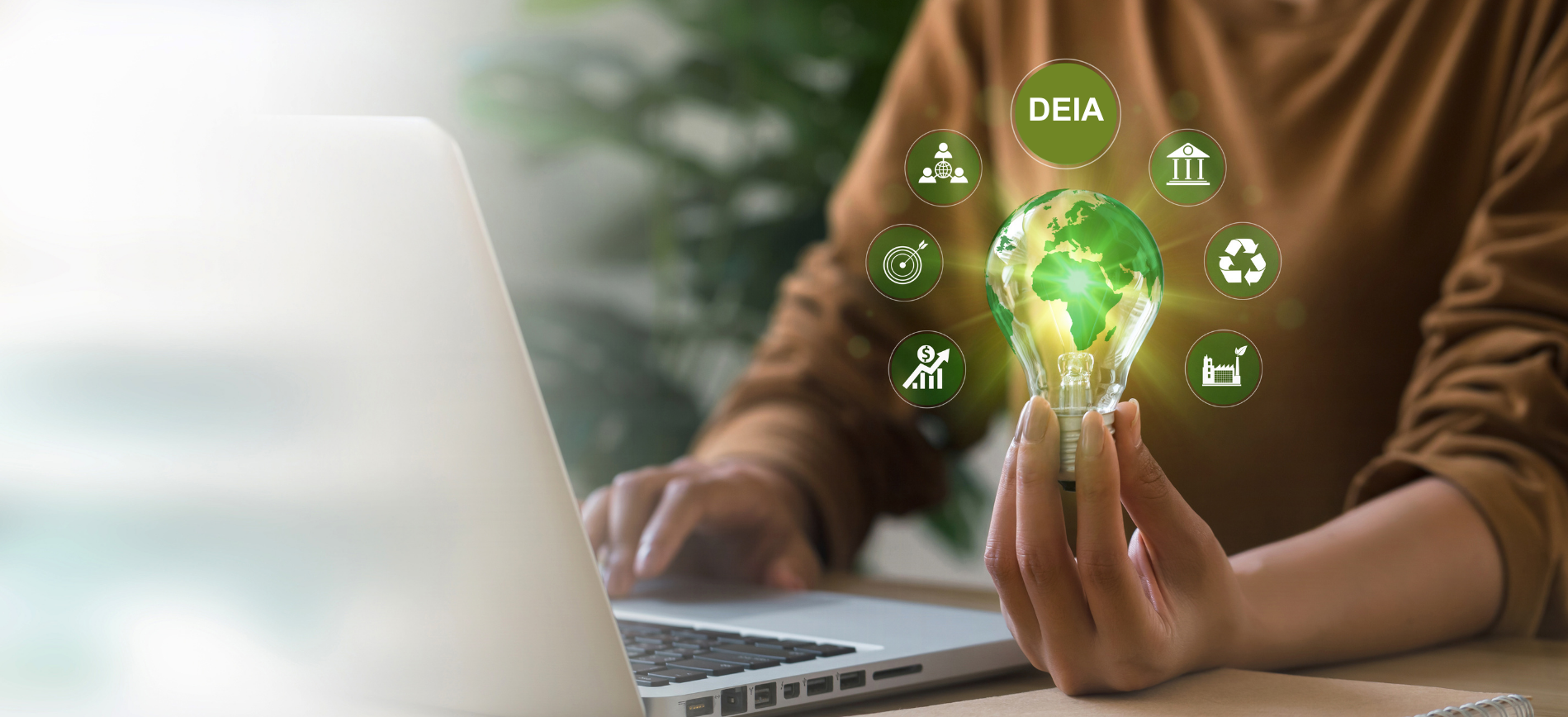 A person at their laptop holds a light bulb with the world inside - various DEIA and ESG bubbles sur