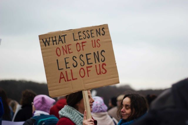 A group of people where one is holding a sign that reads, 